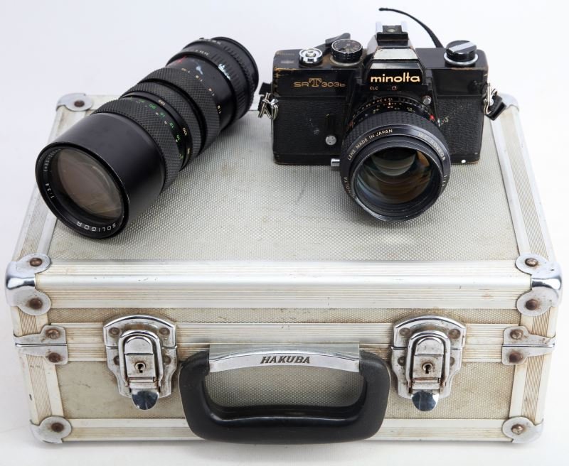 MINOLTA SRT 303B CAMERA WITH CASE AND LENSES: Camera comes boxed in metallic case and features a mc Rokkor Minolta lens and Minolta Macro lens. Some loss of paint to the camera; overall in good condition.