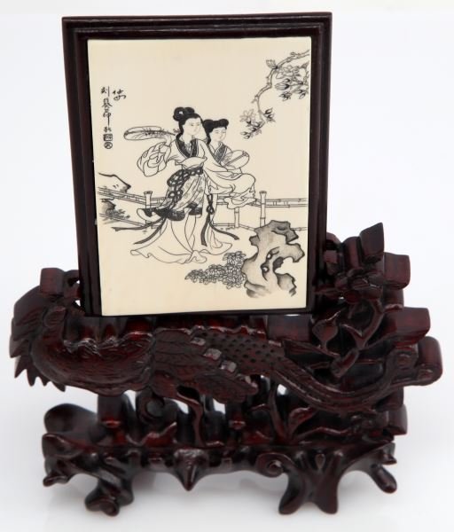 JAPANESE ETCHING ON IVORY PLATE WITH ROOSTER STAND: Plate measures approximately 3 by 4.5 inches and features a drawing of two Japanese women by a cliff side scene. Ivory plate clips into a wooden rooster display. Wood is split on the backside affixed 