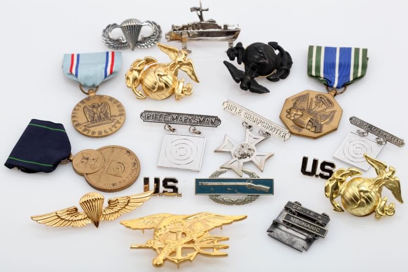 EX DEALERS LOT OF INSIGNIA BADGES AND MEDALS: Group includes a sterling paratrooper jump wings, sterling driver mechanic badge with sterling bars, three Marine Corps EGAs, one CBI, a pair of US collar tabs, paratrooper wings (not sterling), Marin
