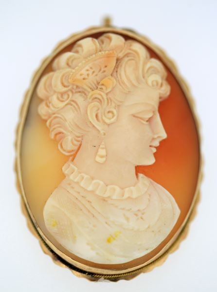 LADIES 10KT YELLOW GOLD CAMEO BROOCH/PENDANT: Large frame, fluted border, containing shell cameo depicting Spanish lady Size: 42.5MM X 31MM Weight: 9.4grams gross// 6.3g in gold Condition: Very good. This lot has a reserve.