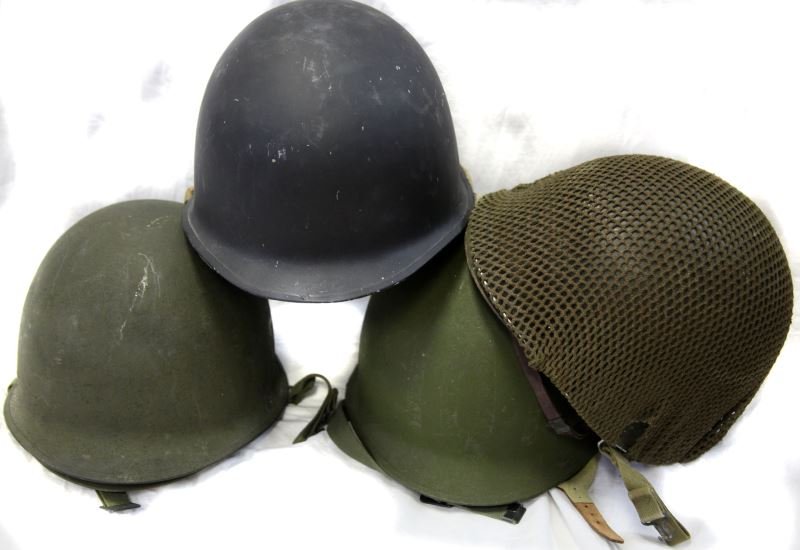 FOUR WWII M1 HELMETS BACK SEAM INCLUDES LINERS: Group includes one helmet which has had the airborne chinstrap added, one includes landing netting with "208" marked on the liner with a hand drawn ranking on the front, one is painted either dark blu