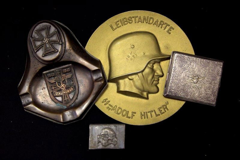 WWII GERMAN CIGARETTE CASE ASH TRAY SS MATCH COVER: Unauthenticated group consisting of Party Eagle (glued) th cigarette case, brass SS serving member door plaque, SS Death Head matchbook cover and a trench art ash tray.