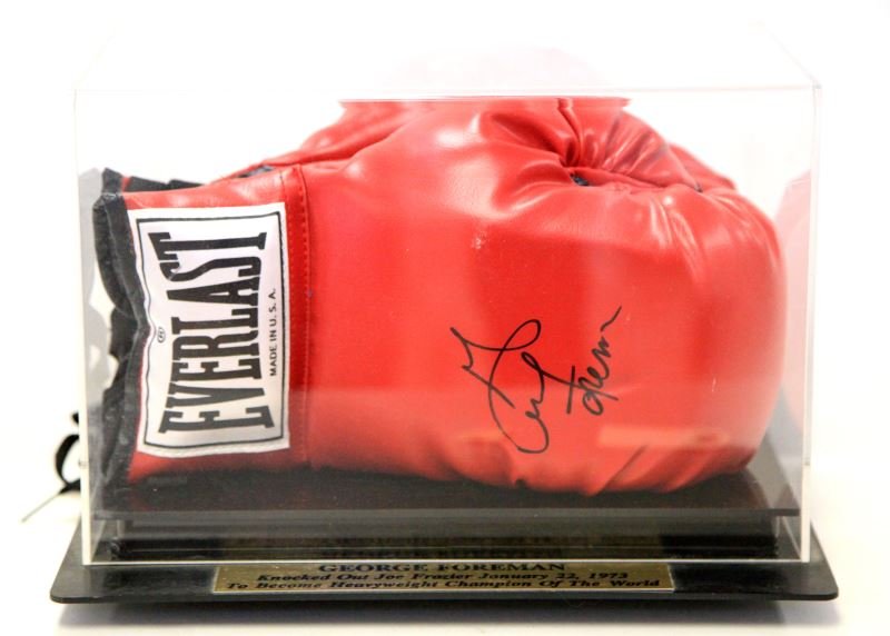GEORGE FORMAN AUTOGRAPHED EVERLAST BOXING GLOVES: Pair of Everlast boxing gloves signed by George Foreman, in a clear display case with a gold plaque that reads "GEORGE FOREMAN Knocked Out Joe Frazier January 22, 1973 To Become Heavyweight Champion O