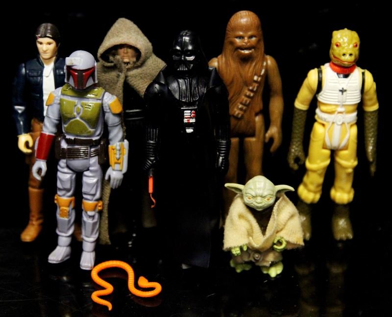 GROUP OF SEVEN 70'S-80'S KENNER ACTION FIGURES: Group includes 1980 Yoda with orange snake, 1980 Bossik bounty hunter, 1977 Chewbacca, 1979 Boba fett, 1982 Luke Skywalker wearing black and brown cloth cape, 1977 Darth Vader with telescoping saber,