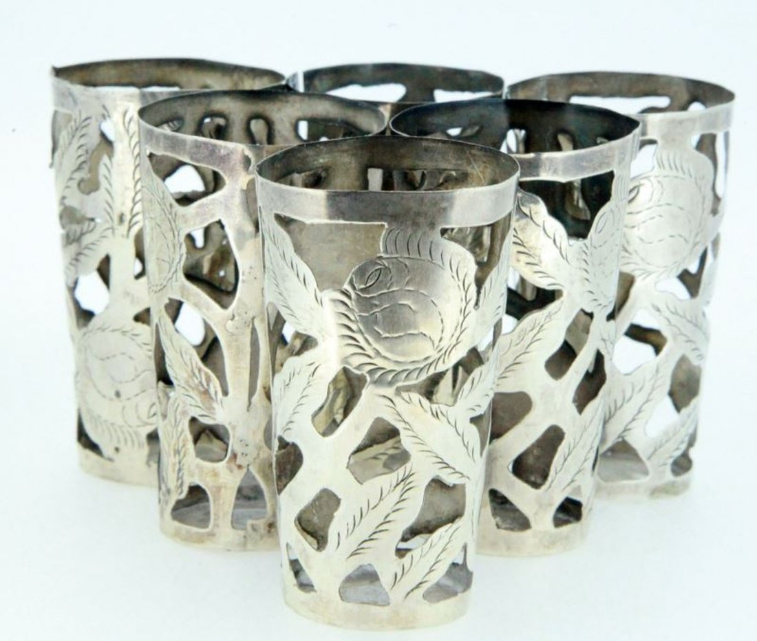 LOT OF SIX VINTAGE STERLING SHOT GLASS SLEEVES: Set of six sterling sleeves for shot glass; each measures 2 1/2 inches tall, 1 1/16 inches diameter at bottom, approximately 1 1/2 inches diameter at top. Hand cut-outs and hand engraving throughout p