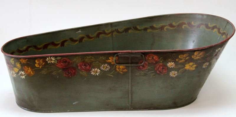 VINTAGE HAND PAINTED TOLE WARE BASSINET BUCKET: Green background with floral motif painted. In the shape of a bassinet with two small handles. Sticker mark to bottom. Overall very good.
