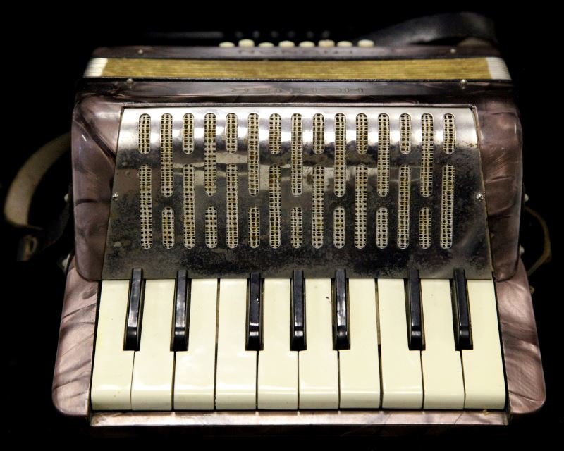 VINTAGE HOHNER "MIGNON" SMALL PIANO ACCORDIAN: Measuring 8 3/4 inches wide, 8 inches tall, 5 inches deep. "Art Deco" design, with pearl finish with red/pink colors. This plays wonderfully and sounds even better; no sticky keys, bellows in top cond