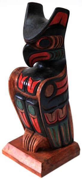 PACIFIC NORTHWEST COAST SINGLE FIGURE CEDAR TOTEM: Hand crafted cedar wood carved single eagle totem. Color palette includes red, black, and some variant of green or blue. Unsigned, measures at 12 inches tall and base is 5 inches wide. In very good co