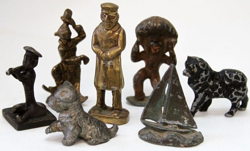 ANTIQUE METALWARE BRASS BRONZE FIGURINES MIXED: Antique Metalware figurines lot of 7. To include: a Barclay Manoil 784 Landing Parachute Man Lead Figure, a brass clown with tipping hat, an alloy doorman, a pewter sailboat, pewter lead dog, a lighte