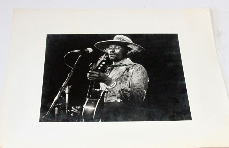 TAJ MAHAL BLUES MUSICIAN BLK & WHT PHOTO 1976: Measures 14 by 11 inches. Great shot of young musician. Great collector piece. Written on back "Taj '76 Watt Casey, phone number, Richard" in red marker. Watt Casey appears to be the photographer.