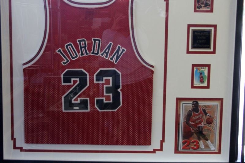 SHADOW BOXED MICHAEL JORDAN AUTOGRAPHED JERSEY COA: Shadow bow measures approximately 41.5 by 33.75 inches. Shadow box contains Michael Jordan signed jersey, two Michael Jordan basketball Cards, one larger image of Michael Jordan dribbling with his ton