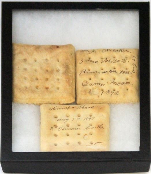 SPANISH AMERICAN WAR HARD TACK FROM CAMP MEAD: Ina glass frame three pieces of original hard tack bread, two of the pieces are inscribed, 3RD Missouri Volunteers, and 2ND Tennessee, and dated 1898.