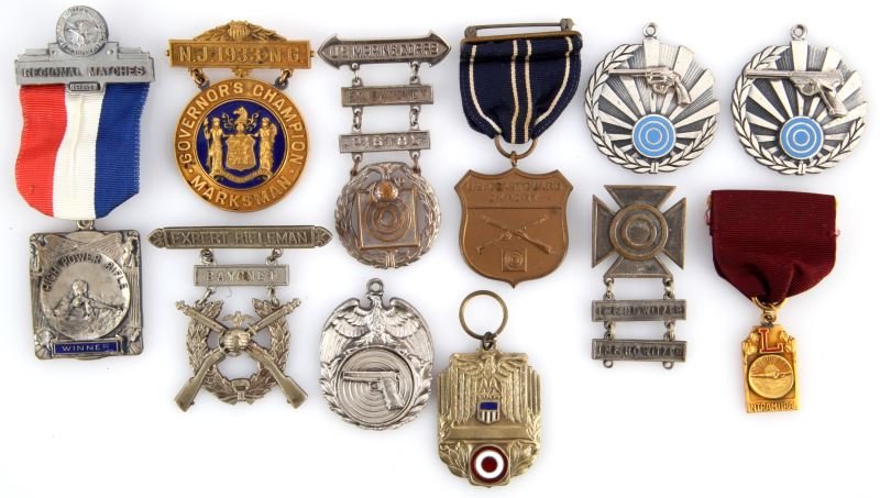 LOT OF 11 SHOOTING AWARDS AND MEDALS 1933-NEWER: Included is a NGNJ Governors Champion Marksman medal from 1933, a USMC (old style EGA) Ex. Bayonet & Pistol pin(pin being absent), a USMC Expert Rifleman & Bayonet pin, an Army marksman pin with two (
