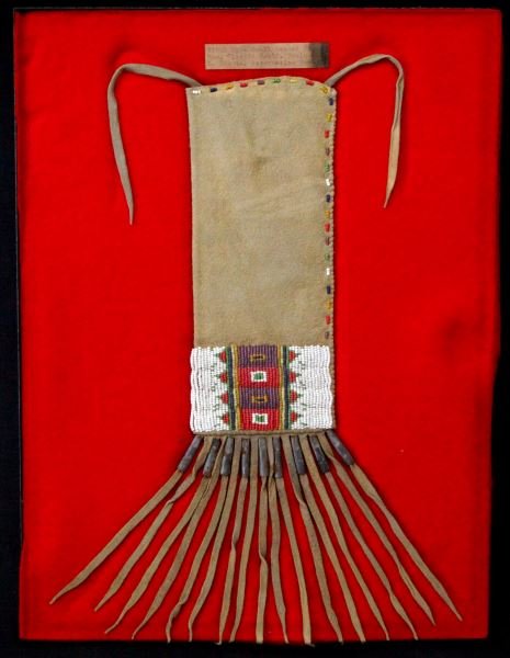 RESERVATION ERA SIOUX BEADED PIPE BAG WITH TASSELS: South Dakota Sioux pipe bag. Reservation era (1871-1928). Brain tanned leather, beaded design to front, metal tubes to tassels. Museum quality. This lot has a reserve.