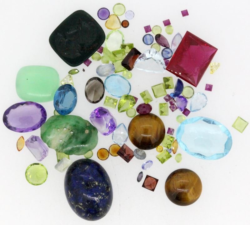 DEALERS LOT LOOSE SEMI-PRECIOUS STONES 101.5CT TW: Including: tiger-eye, jadeite, lapis lazuli,red spinel intaglio, bloodstone intaglio, Swiss blue topaz, sky blue topaz, amethyst, Moz garnet, rubies, peridot, smoky quartz, citrine, morganite. This lo