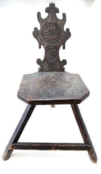 ANTIQUE CARVED WOODEN 3 LEGGED CHAIR W CROSS: Antique wooden 3-legged chair (maybe spinning wheel chair?) Scroll carved design back, 3 large bolts connect seat to legs, mid-relief. Mandala design to middle of back and seat, cross at top appears t