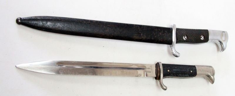 2 WWII GERMAN WALKING OUT DRESS BAYONETS 1 W SCAB: Two Walking out / dress bayonets, one with scabbard. Both have chrome finish and black cross-hatched grip. One is modeled after the German model marked (ERTRA-QUALITAT) (severed tip and pitting to bla
