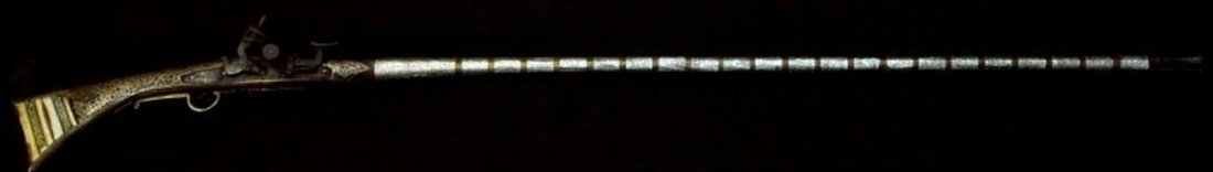 SILVER AND BRASS NORTH AFRICAN SNAPHAUNCE MUSKET: 52 inch engraved silver and brass wrapped barrel, 67 inches long overall. Silver inlaid wood and bone stock. Overall in very good condition.