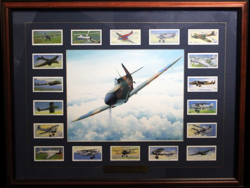 BRIAN KNIGHT SPTFIRE PRINT WITH 18 CIGARETTE CARDS: 8 by 10 colour print of a Supermarine Spitfire surrounded by 18 British war plane cigarette card reprints. Overall framed size is 18 by 22 and is glassed on both sides t allow the viewing of the back