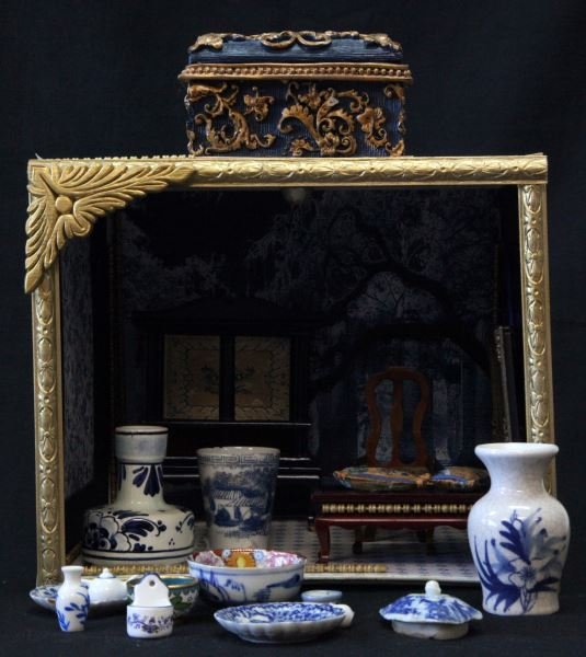 HAND MADE MINI DOLLHOUSE W FURNITURE & PORCELAIN: Handmade small miniature dollhouse. Cardboard construction with floral and Oak tree wallpaper decor, gilt wood frame. Measures 10 by 8 by 8 inches. Furniture, mini porcelain vases, platters, etc. incl