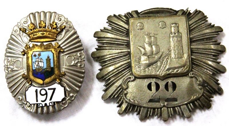 SANTANDER SPAIN NUMBERED ANTIQUE POLICE BADGES: Two antique police badges from Santander, Spain. The oldest is numbered "22" and is pressed tin. The pins on the back are absent and it has a mounting grommet permanently attached. The second is numbe