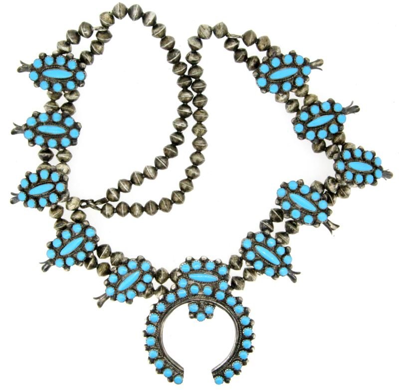LADIES SILVER TURQUOISE SQUASH BLOSSOM NECKLACE: Center Naja piece measures 63mm tall, 53mm wide. Ten smaller blossom measures 33 x 20mm. It appears all stones have been dyed. Necklace is 24 inches long. This lot has a reserve.