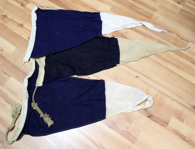 GROUP OF 3 WWII NAVAL SIGNAL REPEATER PENNANTS: 3 WWII Naval Repeater pennants. Blue and white with rope and all markings evident (1944). One is completely discolored in the white, minor staining to others. Wear appropriate for age and use.