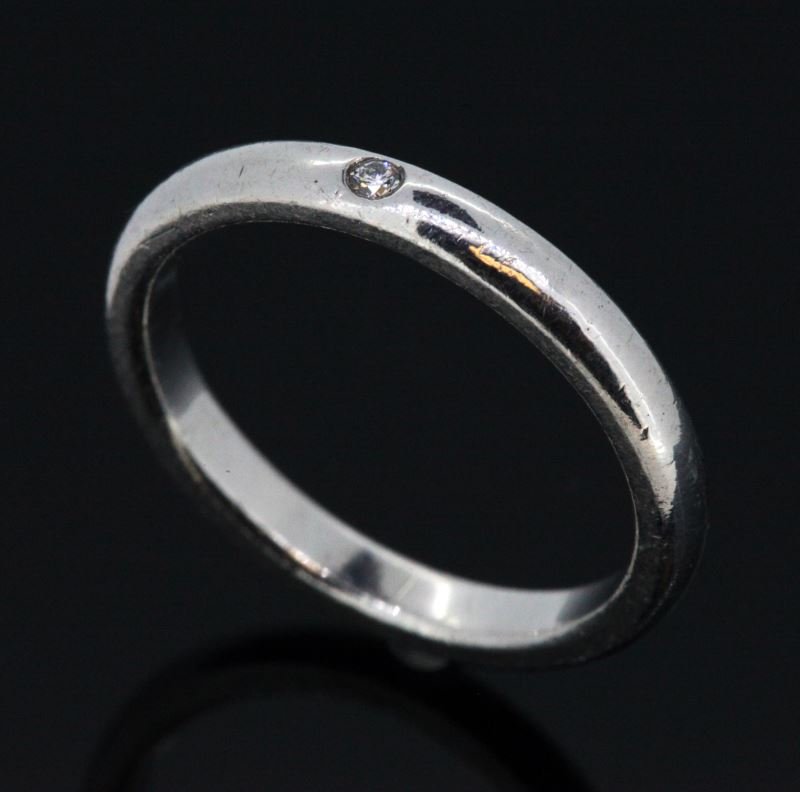 LADIES STERLING DIAMOND BAND TIFFANY & CO PERETTI: Marked on inside of ring: "Peretti 925 Tiffany & Co.", 2.7mm wide, 1.9mm thick, featuring one round brilliant cut diamond, weighing approximately .03cts, bezel set into band. Size 7. Weighs 2.6 grams.