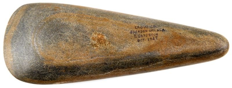 ALABAMA NATIVE AMERICAN POLISHED STONE CELT: Smooth stone celt found in Crow Creek Jackson County, Alabama in 1921. Late Archaic to early Woodland period. 9 Inches long and 3.5 inches wide at the widest point. The stone is dark grey with brown p