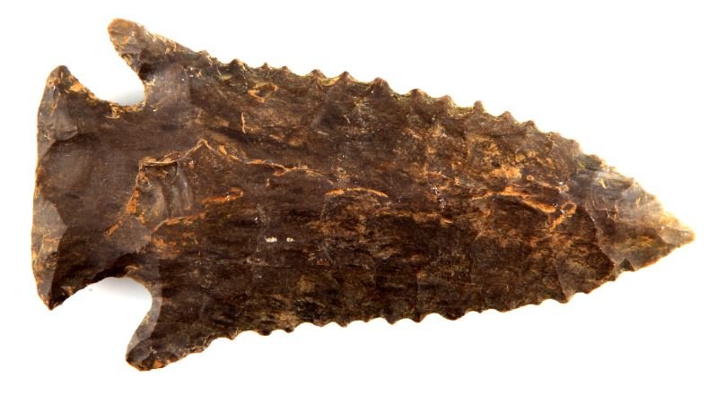 LATE ARCHAIC SERRATED KIRK ARROWHEAD ALABAMA: Late Archaic Kirk arrowhead. Dark grey flint corner notched point, Alabama. Wear patina to sight and touch. Well chipped blade, broad stroked to one side, one barb is higher than the other. Measures 3