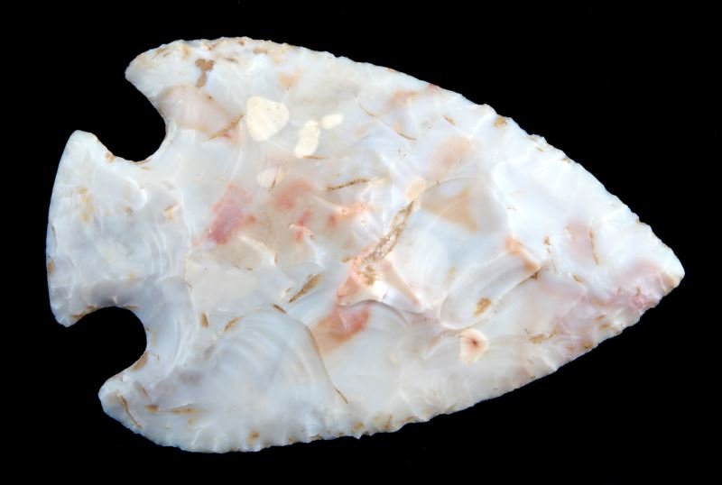 WOODLAND SYNDER HOPEWELL ARROWHEAD POINT: Synder Hopewell arrowhead point, Woodland. Made of translucent white stone with reddish inclusions (maybe coastal plains chert). Broad random flaking with secondary chipping. Ground base. Measures 3.2