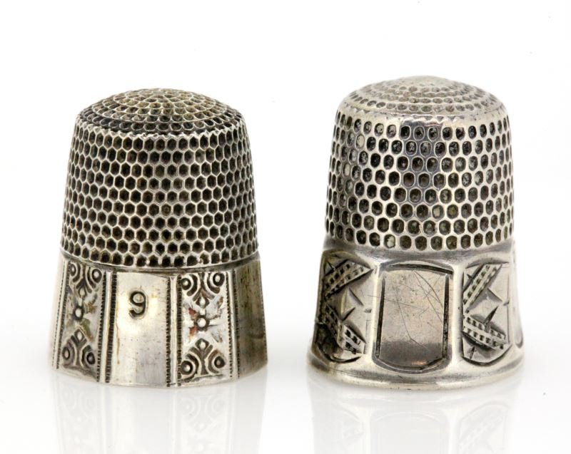 TWO ANTIQUE SIMON BROTHERS THIMBLES SILVER: Lot of two Simon brothers antique thimbles, one is silver while the other is not. Both has alternating geometric patterns on their lower bands. One thimble is out of round, but they are in overall ver