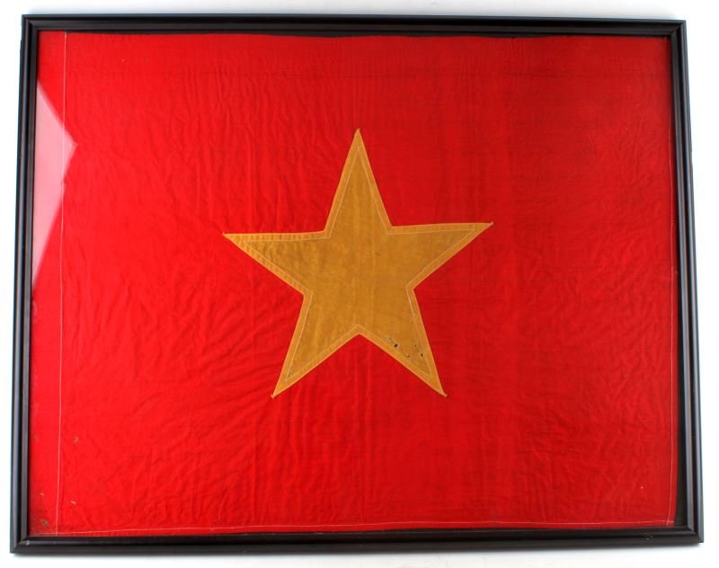 NORTH VIETNAM STANDARD FLOWN IN BATTLE: Vintage North Vietnam flag, flown in battle. The flag is framed, but appears to be made out of cotton. The stitches attaching the star to the field are visible. The is a seam along the left edge of th