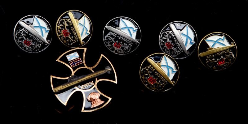 LOT OF 7 RUSSIAN BADGES LIFTING OF SUBMARINE KURSK: Seven Russian badges devoted to the lifting of the submarine Kursk: three small gold colored badges, three small silver colored badges, and one larger badge. Unauthenticated as is.