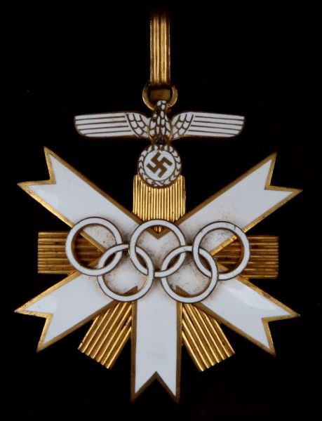 WWII GERMAN THIRD REICH WHITE ENAMEL OLYMPIC MEDAL: White Third Reich enamel First Class Olympic medal. White enameled Olympic rings on white ribbons. Parteiadler in white enamel at the top. Two rivets in back indicate two piece construction. Measures