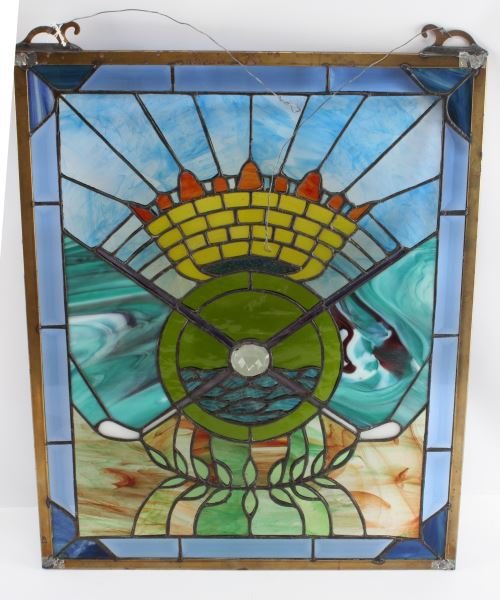 GOLF STAINED GLASS PANEL 16 BY 20.25 INCHES: Golf themed stained glass panel with vertical orientation. The piece uses solid and streaky glass pieces. The piece depicts cross golf clubs below a rising sun. The frame has some tarnishing but overa