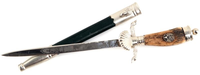 WWII GERMAN THIRD REICH MINI STAG HORN DAGGER: Third Reich miniature dagger with stag horn handle. Features a round pommel, a stag horn handle with metallic swastika motif, stag leg cross guards, and a seashell guard. The blade is etched with styl