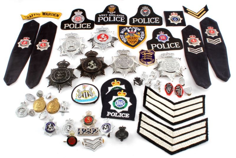 LOT OF ENGLISH POLICE INSIGNIA HELMET BADGES ETC: Large lot of English police items. Lot includes: 2 King's Crown helmet plates, Queen's Crown helmet plates, chevron rank insignia, police shoulder patches, pins, and shoulder straps. Includes London, 