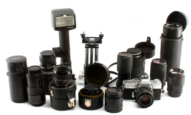 LOT OF MINOLTA LENSES PLUS CAMERA AND EQUIPMENT: Large lot of Minolta film camera equipment. Contains one Minolta SRT 102 camera with 50 mm prime lens, one Minolta macro bellows, Minolta AF 50mm 1.7 lens, Minolta handheld flash, MC Rokkor 50mm 1.4 M