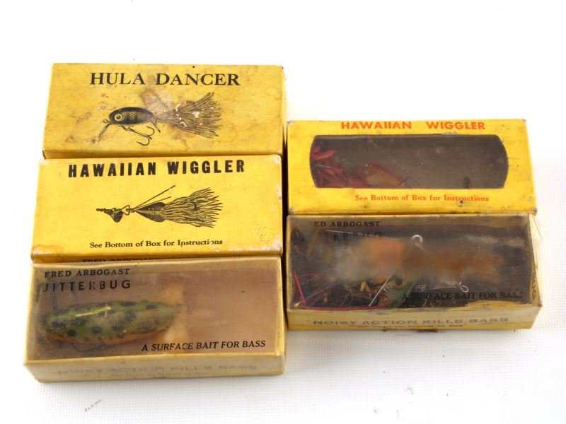 5 VINTAGE LURE BOXES W LURES HULA JITTERBUG: Five vintage lure boxes with lures: one Hula Dancer box with lure, two Jitterbug boxes with lures, and two Hawaiian Wiggler boxes with lures. By Fred Arbogast. Expected signs of age and wear.