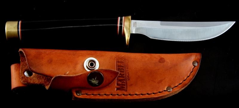 MARBLES FIXED TRAILING POINT BLADE KNIFE W/ SHEATH: Four inch trailing point blade. Black stained wood handle with white and red accents. Brass handguard and pommel. Includes a brown leather sheath.