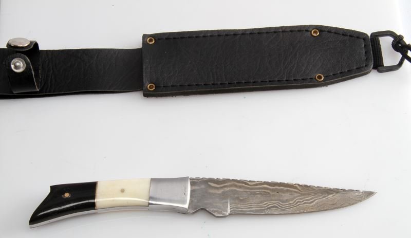 CUSTOM DAMASCUS STEEL HUNTER'S KNIFE W HORN HANDLE: Custom made hunting knife. Has a fixed 5 inch Damascus steel blade. White and black horn handle. In very good condition. Includes a black leather sheath.
