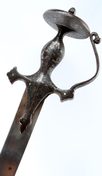19TH C. MIDDLE EASTERN PERSIAN SHAMSHIR SWORD: A curved shamshir sword with wooden scabbard and finely decorated handle. Its blade is in good condition with very little oxidation. Its metallic handle has been inlaid with gold and silver floral mot