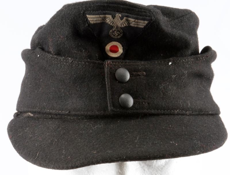 WWII THIRD REICH BLACK WOOL M43 CAP WITH INSIGNIA: A black wool M43 cap with trapezoid patch containing Heer eagle and cockade. Matching black pebbled buttons. Free of mothing and in very good condition. Some staining on interior lining. Small in size