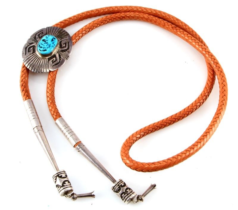 THOMAS SINGER NAVAJO BOLO TIE SIGNED STERLING: Stamped sterling silver with turquoise bolo tie by Navajo artist Thomas Singer. Brown leather strap with silver and turquoise inlayed central piece and sterling tips. Very good condition. The roundel