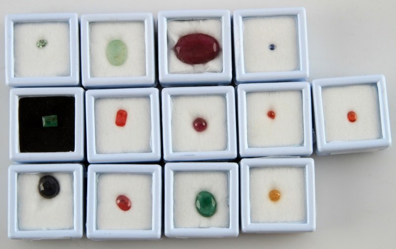 LOT OF 13 PRECIOUS GEMS SAPPHIRE / EMERALD / RUBY: Various precious gems, including sapphires (green, orange Songea, Padparadsha, blue and yellow), rubies (cab and step cut), and emeralds (step cut and carved). Sold as is. All in containers.