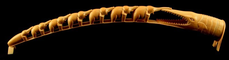 PRE BAN IVORY TUSK CARVING ELEPHANTS AND CROCODILE: A carved tusk depicting small elephants and a large crocodile. Measures 22.5 inches long. Some loss to elephant ears, tusks and trunks.