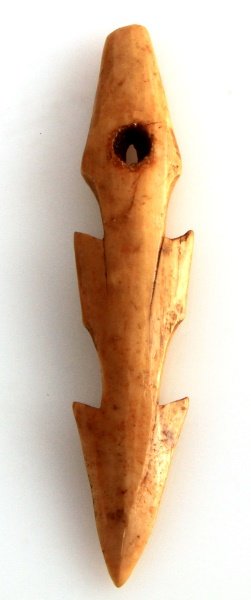 NATIVE AMERICAN CARVED BONE FISHING SPEAR TIP: A Native American fishing barbed fishing spear tip crafted out bone. Measures 4 5/8 inches long. Has two sets of barbs on each side plus a perforation near the base with two shoulders at each side of 