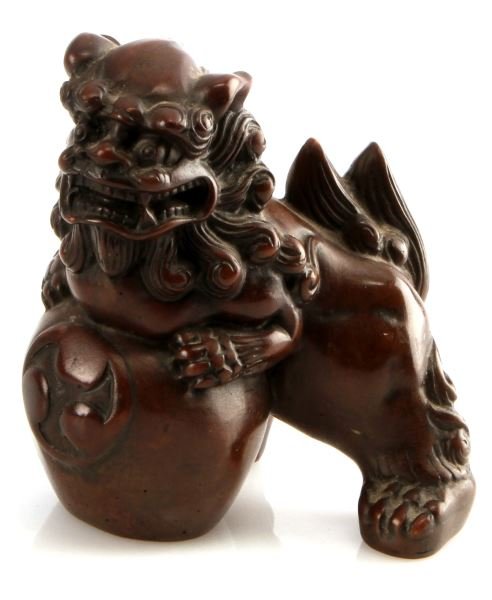 CHINESE CARVED BROWN SOAPSTONE FOO DOG LION: A 3 7/8 inch tall brown soapstone Chinese guardian lion or Foo Dog with its front paws on a sphere. In very good condition.