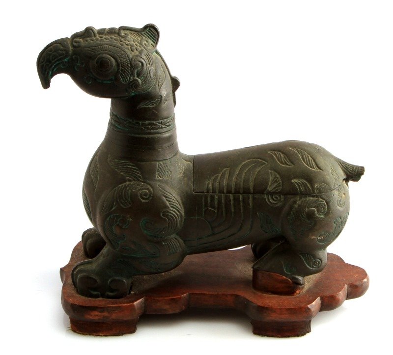 VINTAGE ASIAN CARVED BRONZE STATUE CIGARETTE CASE: Carved Asian zoomorphic bronze on wooden stand. Incised design shows verdigris. Head comes off to display Prince lighter. Tail pushes open to display wooden case for cigarettes. Measures 10 by 9 inche
